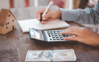 Person writing in notebook and using calculator