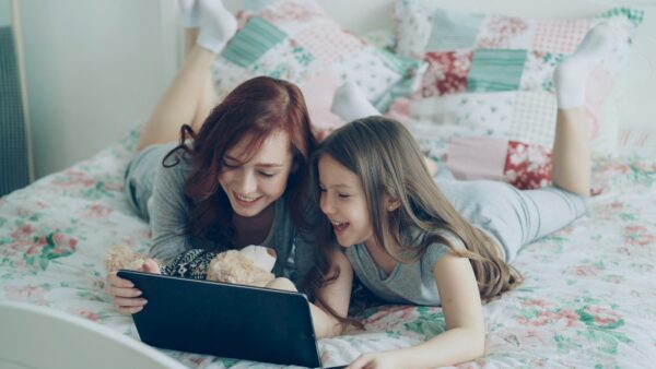 girl and her sister looking the computer and smiling